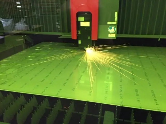 A machine cutting sheet metal with sparks flying.